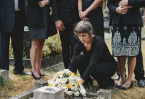 Mourning family placing Christmas memorial flowers of white and yellow on a grace