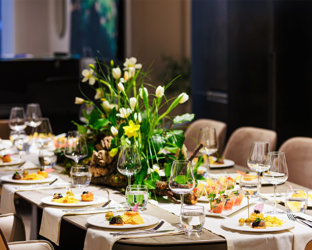 Elegant Floral Centerpiece With White Tulips And Lush Greenery On A Luxurious Dining Table, Ideal For Sophisticated Events, Weddings, And Fine Dining Decor.