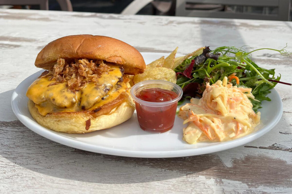 Deluxe burger with salad, crisps, coleslaw, and ketchup on the outside terrace of Williamson's café in Livingston, West Lothian