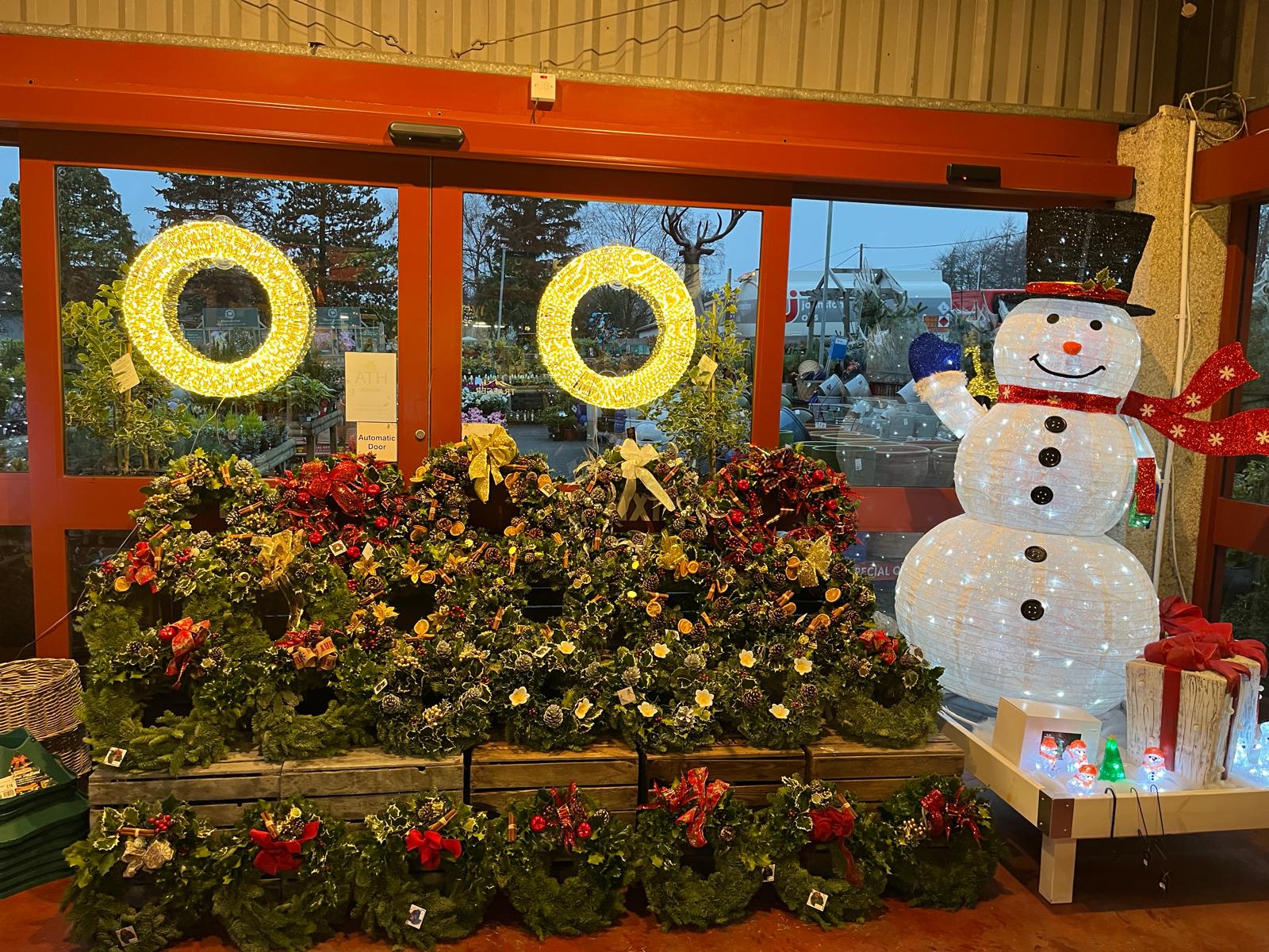 Christmas wreaths at Williamson's garden centre entrance Christmas wreaths displayed at the entrance of Williamson's garden centre at dusk, with lit wreath rings and a light-up snowman