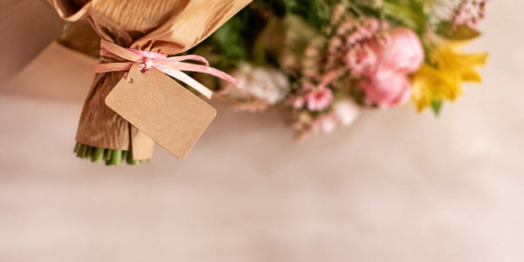 Close-up of a small blank gift tag tied to a wrapped birthday bouquet