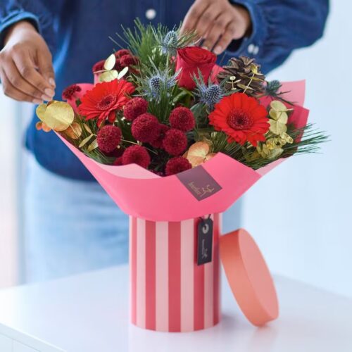 Christmas flower hatbox with red flowers, seasonal greenery, berries and gold accents