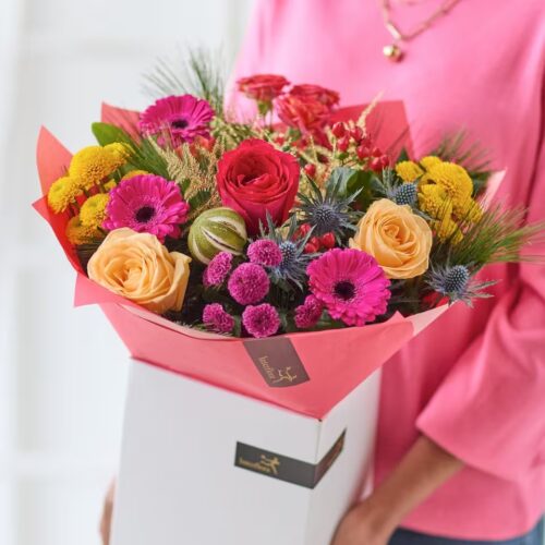 Bright Christmas bouquet with pink, red and yellow flowers, seasonal greenery and dried fruit